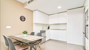A modern kitchen with white cabinets, a dining table with chairs, and a small potted plant. - 'Apartamento caracoles Duna Beach' with Sea View, Wi-Fi, and Air Conditioning (Torrox)