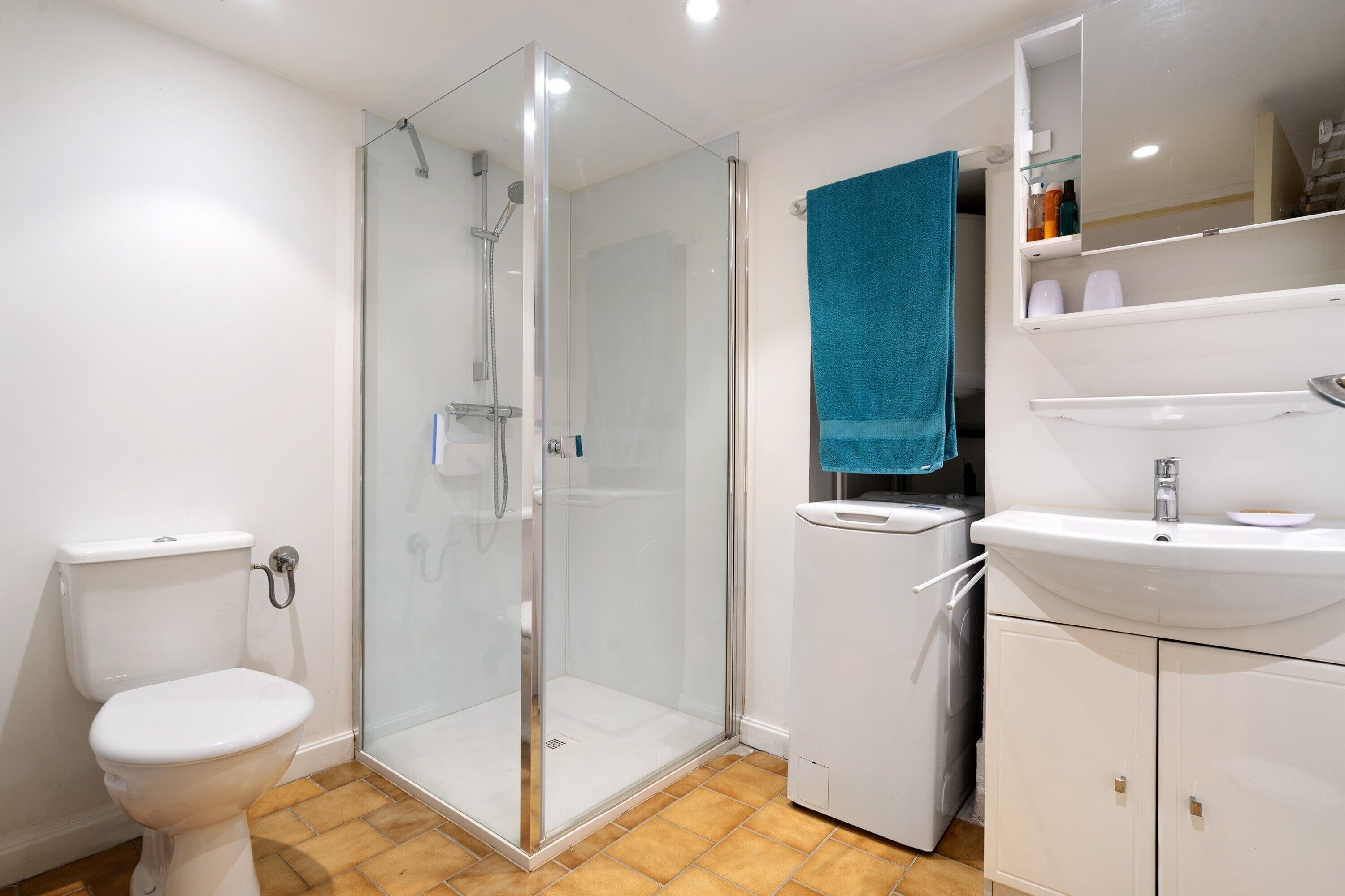Un baño con ducha de vidrio, inodoro, lavamanos y espejo sobre el lavamanos.