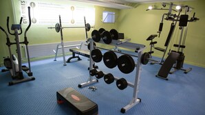 Ett gym med olika typer av träningsutrustning, inklusive hantlar, en träningsbänk och ställ för vikter.