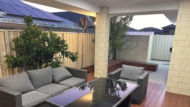 Un área de patio al aire libre con mobiliario de mimbre, incluyendo sofás y una mesa de centro.