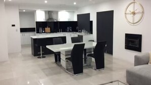 Una cocina moderna con una isla central, sillas negras y una mesa de comedor blanca.