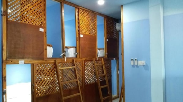 Une pièce avec un mur bleu, des cloisons en bois, une échelle et une porte blanche.