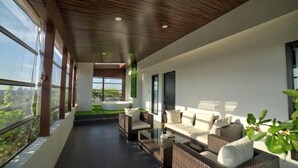 A modern interior with a long balcony, wicker furniture, and large windows offering views. - Goldfinch Hotel Mangaluru (Mangaluru)