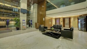 A spacious lobby with a high ceiling, marble flooring, and modern furniture. There are signs indicating the location of different floors. - Goldfinch Hotel Mangaluru (Mangaluru)