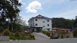 A multi-story building with a balcony, surrounded by greenery and a paved area leading to the entrance. - Rovers Inn Tanah Rata (Tanah Rata)