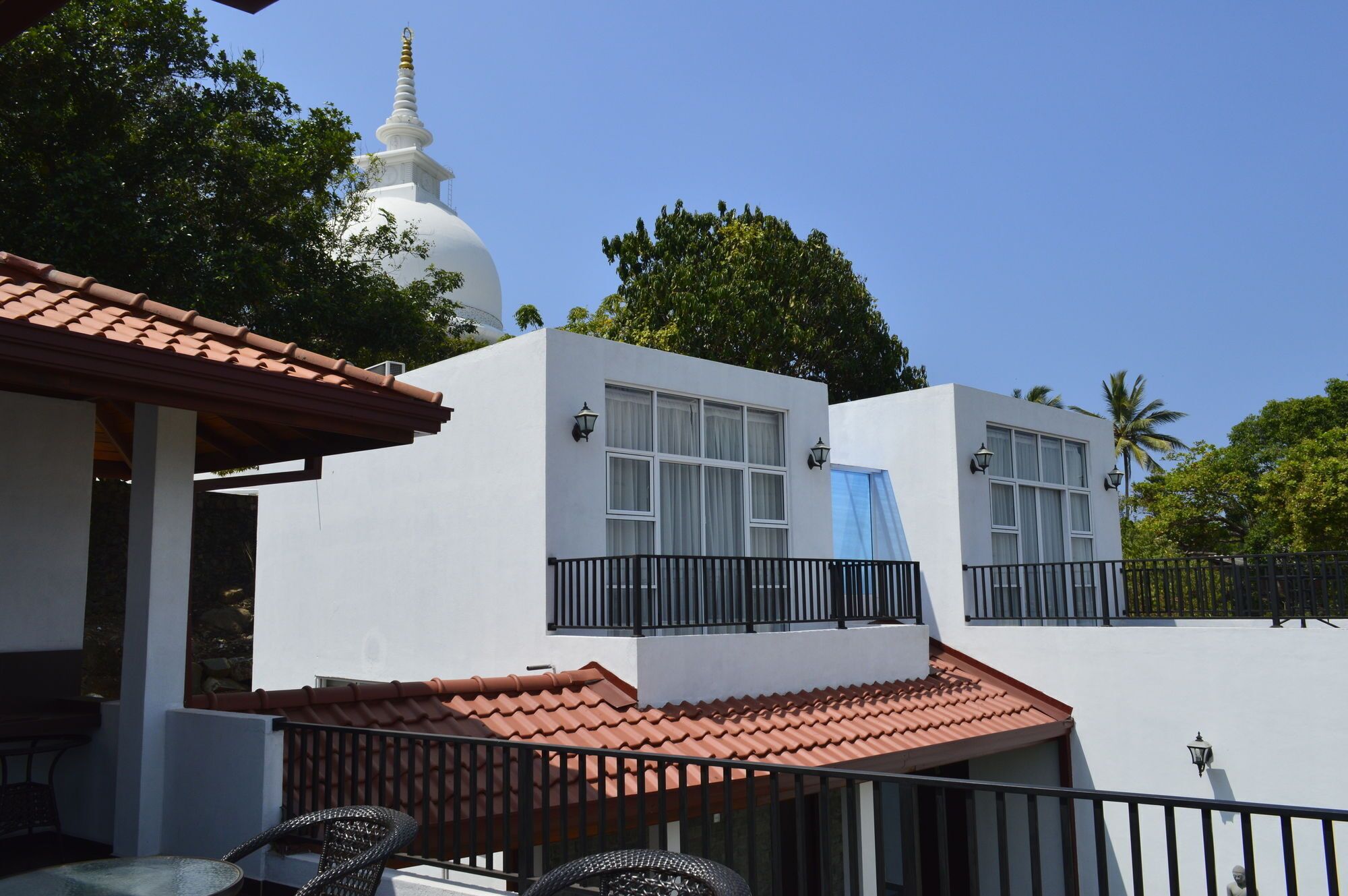 A modern building with a white exterior, a red-tiled roof, and a white dome structure in the background.