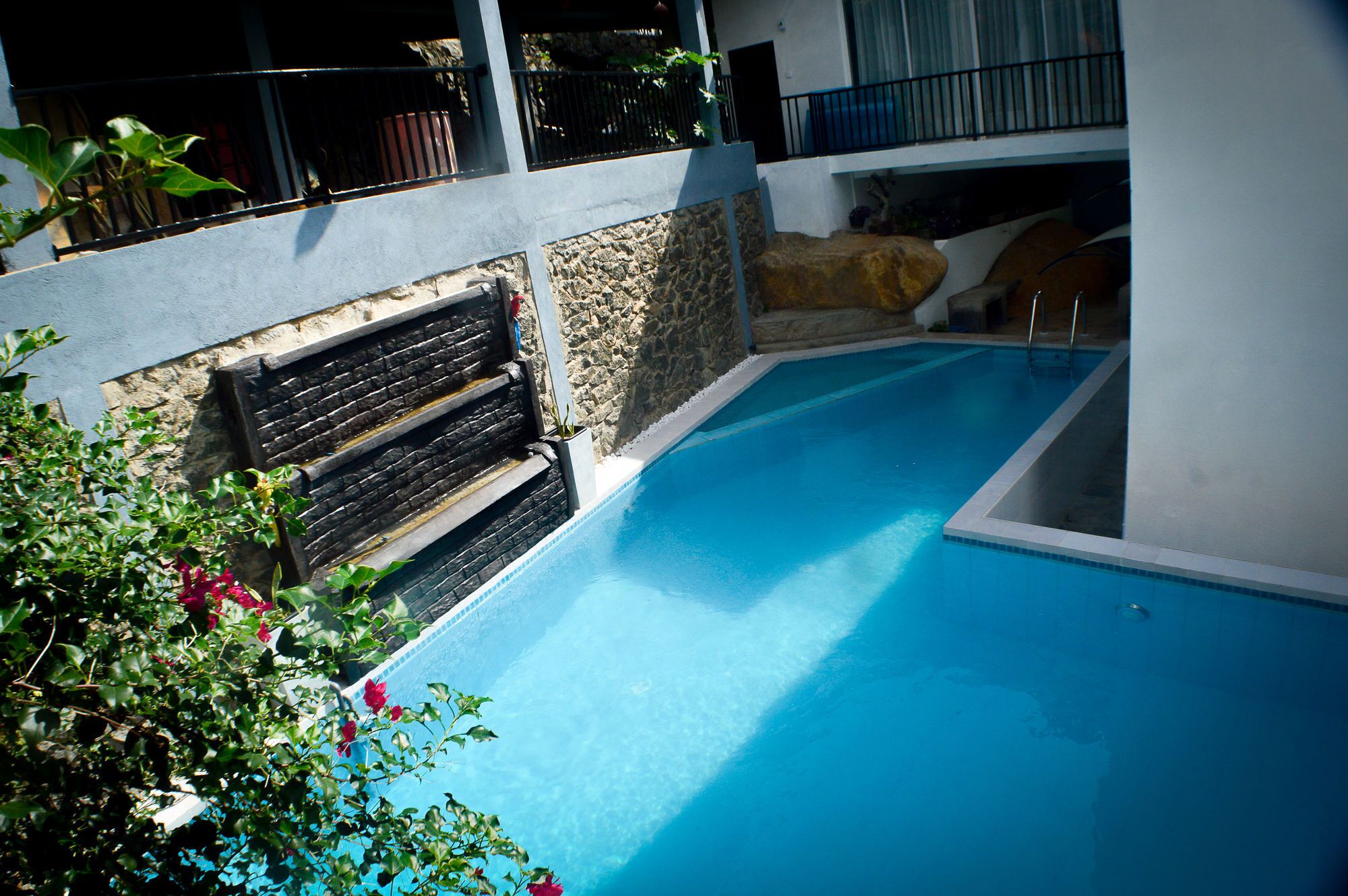 A swimming pool with a stone wall and a wooden bench.