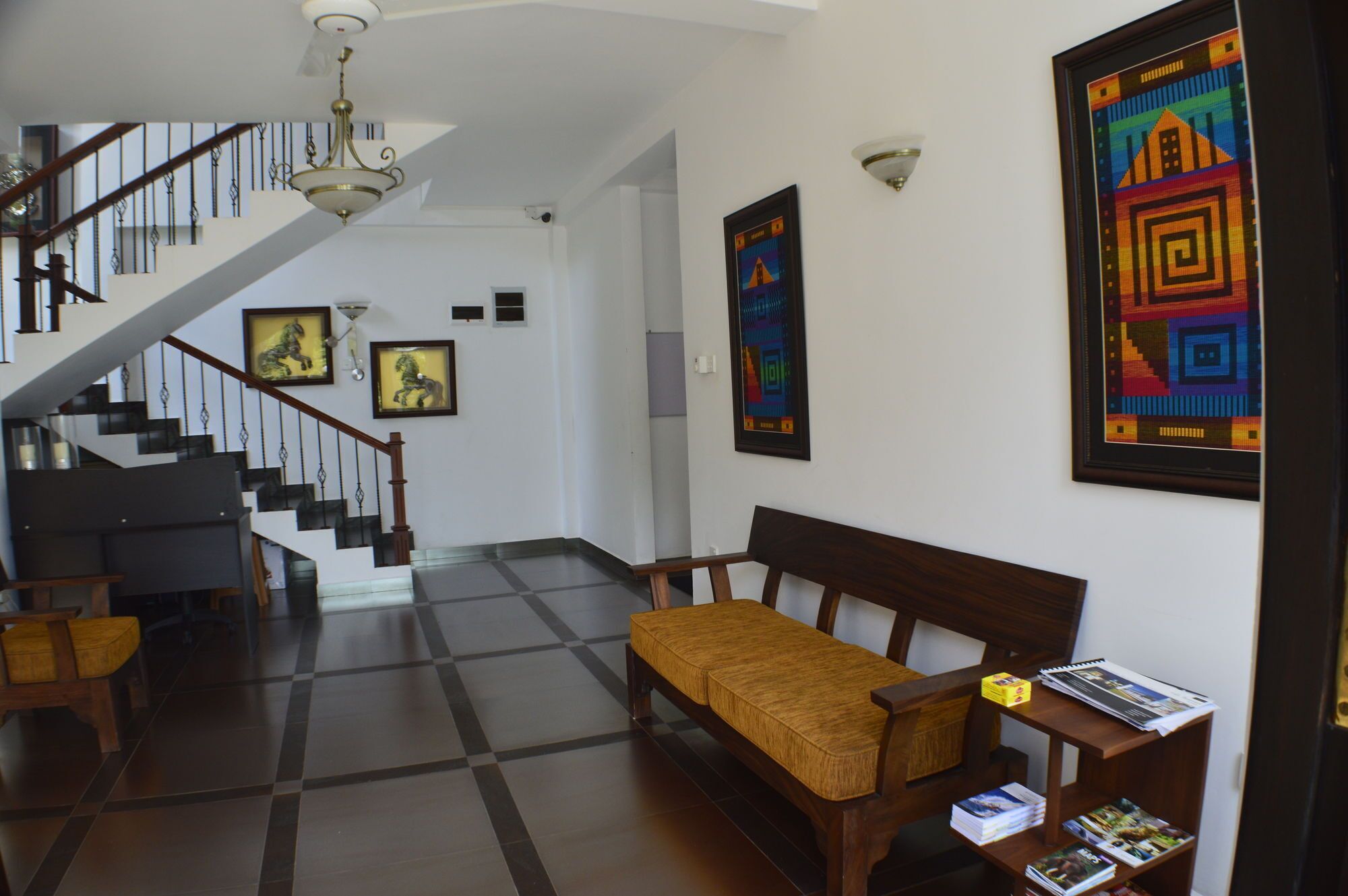 A spacious foyer with a staircase, a bench, and a table with magazines.