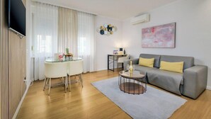 A modern living room with a grey sofa, a glass table, and a round coffee table. - Meridien Luxury Apartments (Zagreb)