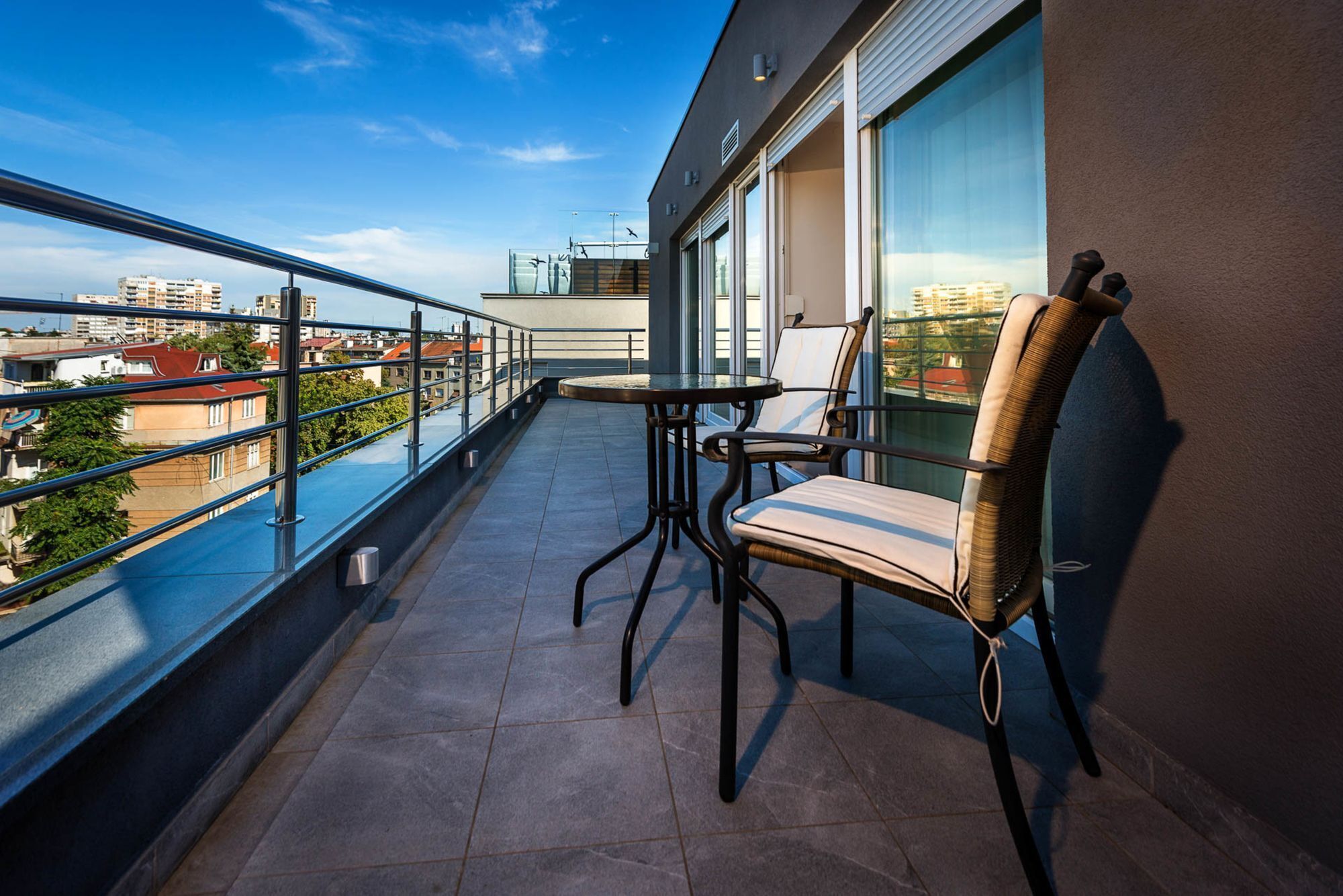 A balcony with a table and chair, offering a view of the cityscape.