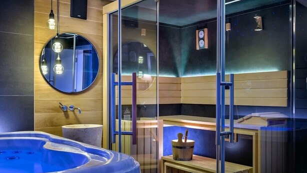 A modern bathroom with a round mirror, a bathtub, and a wooden vanity. - Meridien Luxury Apartments (Zagreb)