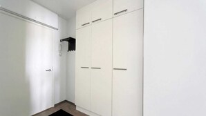 A hallway with a white wardrobe and a black shelf. - Sato Hotelhome Kamppi (Helsinki)