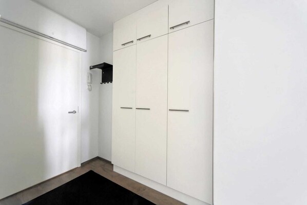 A hallway with a white wardrobe and a black shelf. - Sato Hotelhome Kamppi (Helsinki)