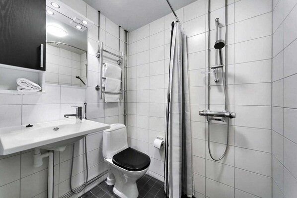 Ein modernes Badezimmer mit Waschbecken, Toilette und Duschbereich in Weiß.