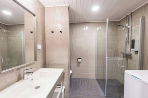 A modern bathroom with a glass-enclosed shower, a white sink, and a large mirror. - Sato Hotelhome Kruununhaka (Helsinki)
