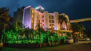 A multi-story hotel with a prominent "BARSANA" sign, surrounded by lush greenery and palm trees. - Barsana Hotel And Resort (Siliguri)