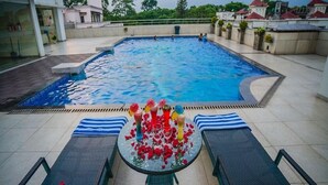 A swimming pool with a glass table in the center surrounded by lounge chairs. - Barsana Hotel And Resort (Siliguri)