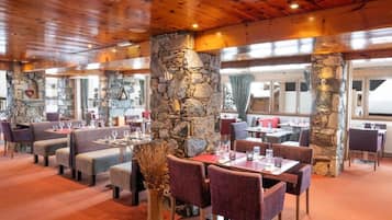 Un restaurant avec des piliers en pierre, un plafond en bois et des tables avec des chaises.