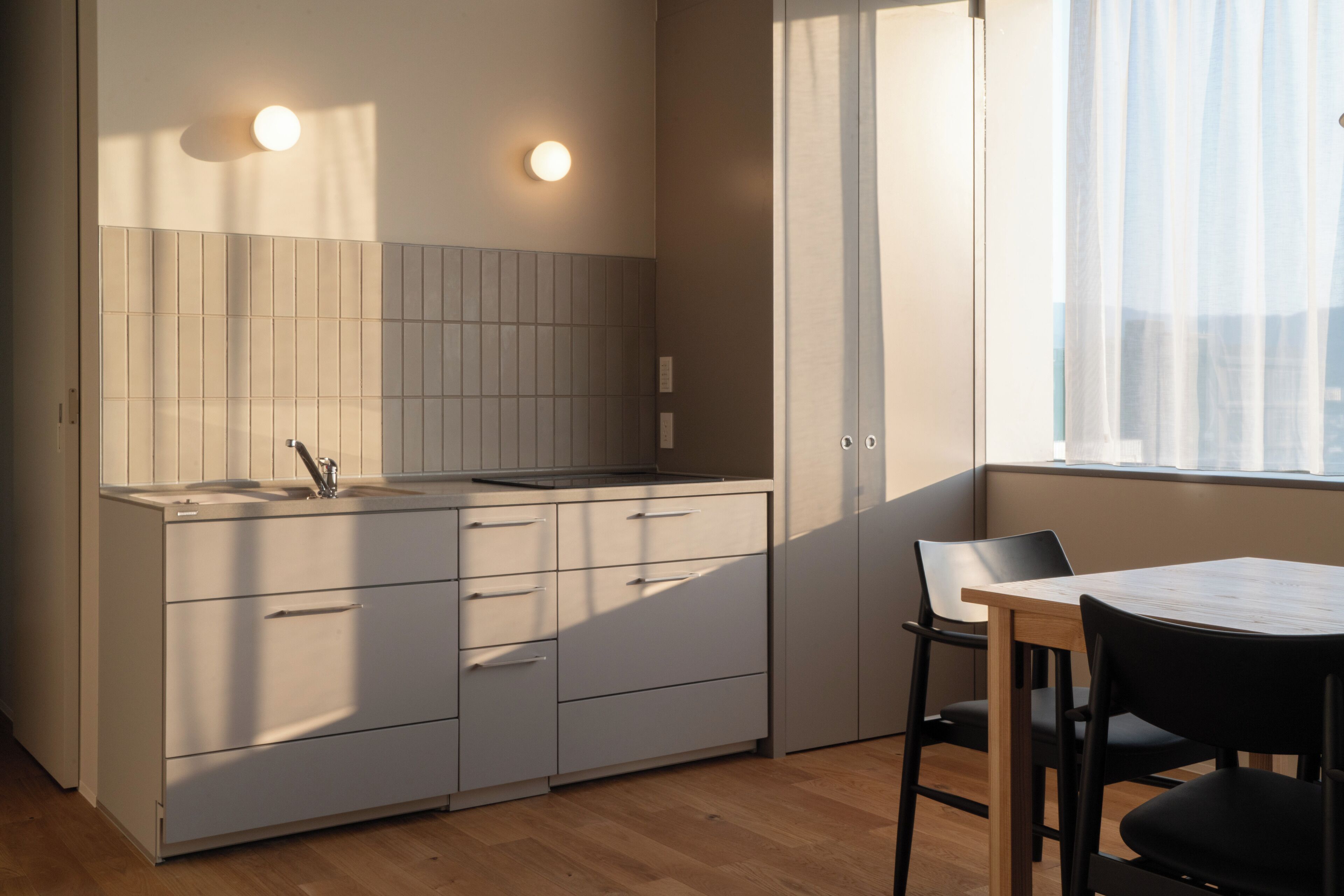 Una cocina moderna con pileta, alacenas y un comedor con sillas y una mesa.