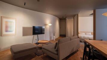 Ein modernes Wohnzimmer mit Flachbildfernseher, rundem Couchtisch und einer Sofagarnitur.