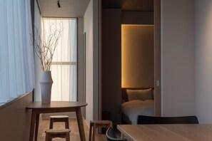 A modern hotel room with a wooden dining table, two chairs, a potted plant, and a bed with a headboard. - goodroom hotel Kyoto (Kyoto)