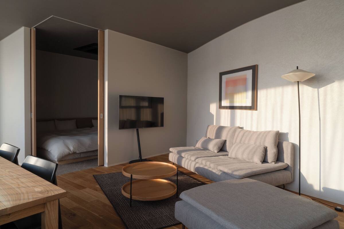 A modern living room with a sofa set, a dining table, and a TV.