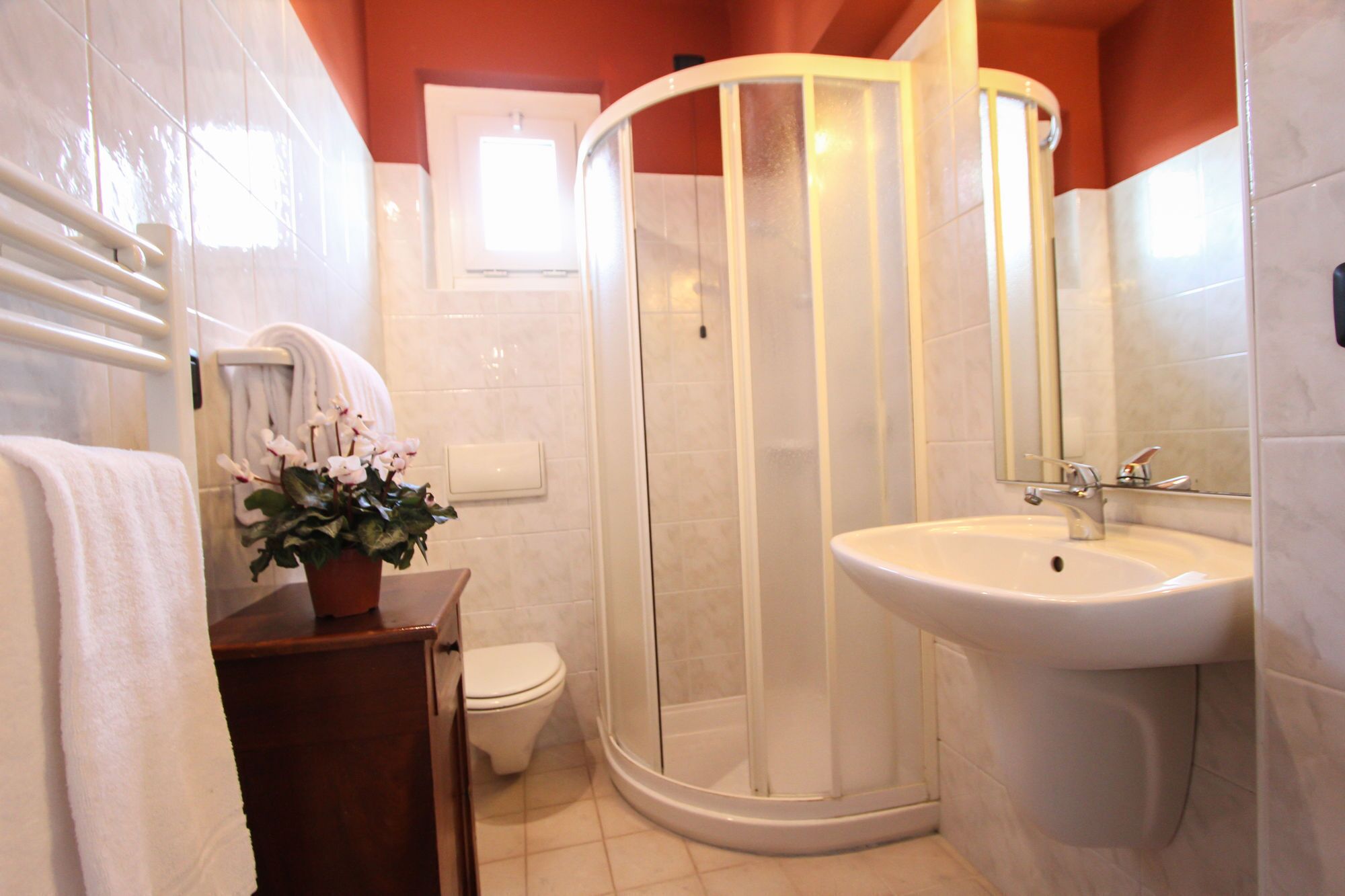 Een badkamer met een wit wastafelmeubel, een toilet, een douchecabine en een potorkidee.