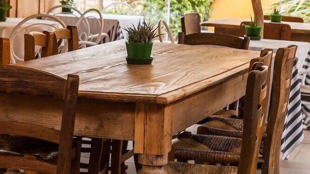 Une table à manger en bois, des chaises, un luminaire suspendu et une vue sur l’extérieur.