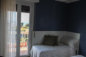 Ein Schlafzimmer mit Bett, einem Fenster mit Vorhängen und Blick ins Freie.
