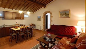 Una sala acogedora con una mesa de comedor, sillas, un sofá rojo y una mesita de centro.