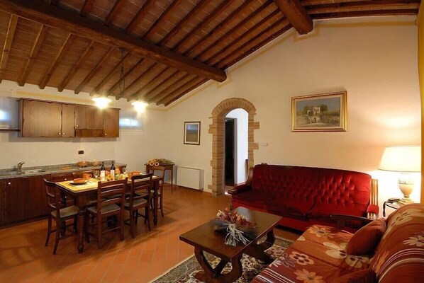 Una sala acogedora con una mesa de comedor, sillas, un sofá rojo y una mesita de centro.