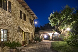 Edificio de piedra con patio, entrada en arco y plantas en macetas.