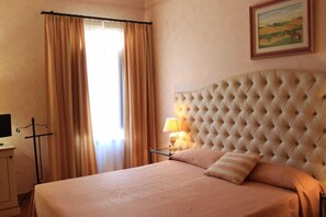 Una habitación de hotel con una cama grande, una lámpara de noche y un cuadro en la pared.