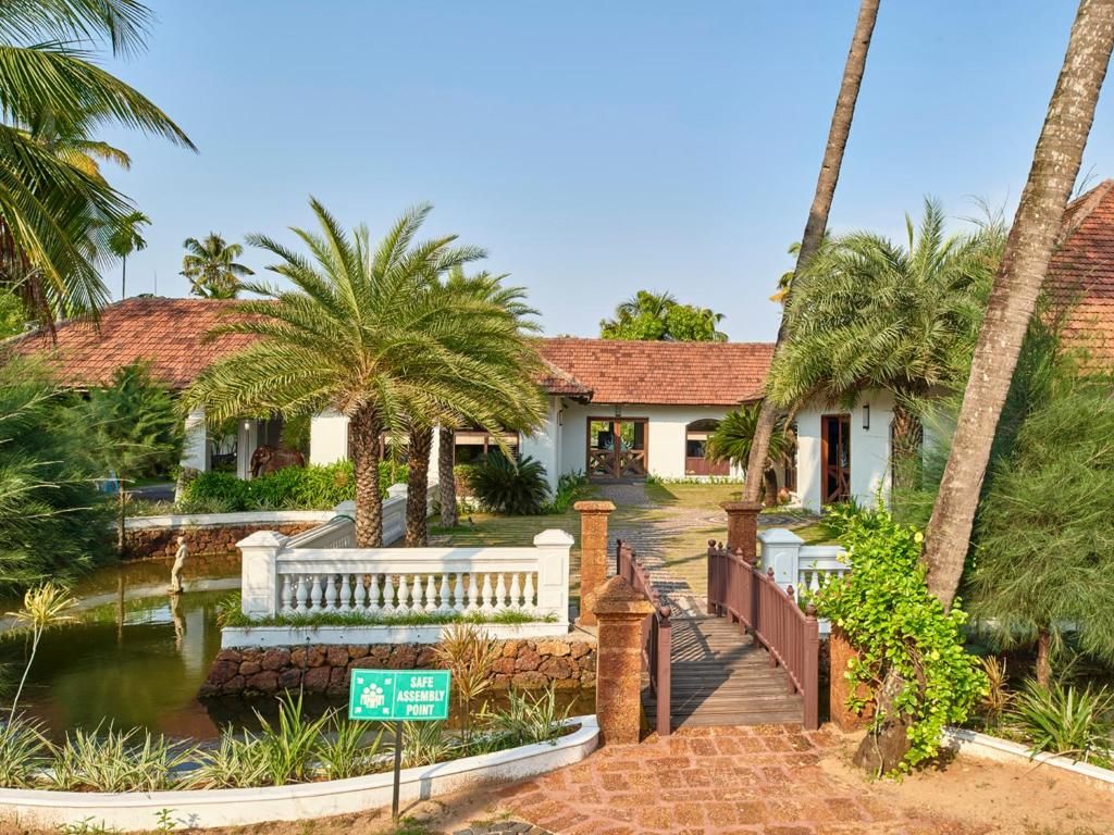 A resort with a pool, palm trees, and a sign indicating a safe assembly point.
