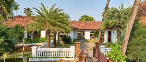 A resort with a pool, palm trees, and a sign indicating a safe assembly point.