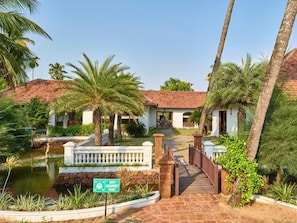 A resort with a pool, palm trees, and a sign indicating a safe assembly point. - Club Mahindra Cherai (Kochi)