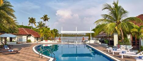 A swimming pool with lounge chairs and palm trees.