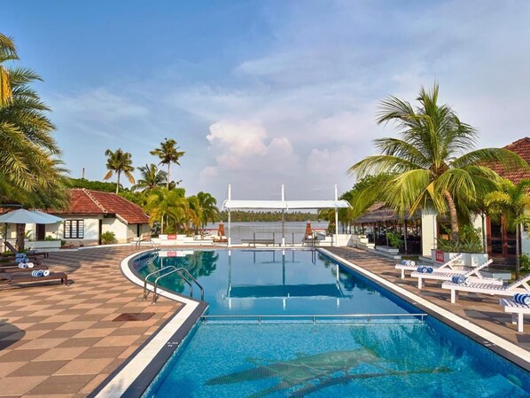 A swimming pool with lounge chairs and palm trees.