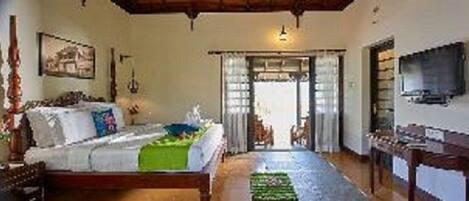 Quarto com cama, televisão e porta de acesso a outro espaço.