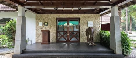 Un acceso cubierto con un muro de piedra, una puerta de madera y una estatua.