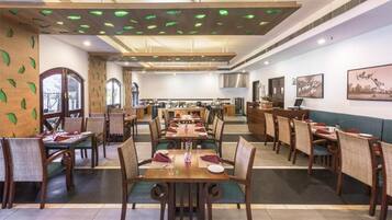 Un restaurante con varias mesas y sillas, un techo con luces verdes y obras de arte en las paredes.