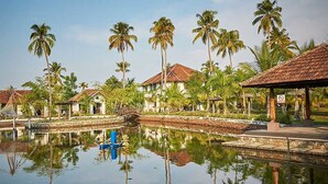 Een resort met een zwembad, palmbomen en gebouwen in traditionele stijl.