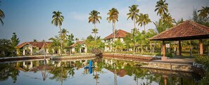 A resort with a swimming pool, palm trees, and traditional-style buildings.