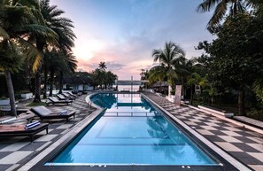 A swimming pool with lounge chairs and palm trees.