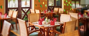 A restaurant with wooden tables and chairs, arranged for dining. - Club Mahindra Cherai (Kochi)