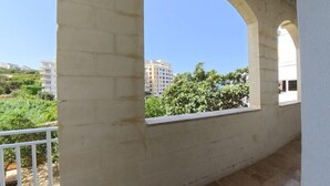 A balcony with a stone floor and white railings, overlooking a residential area with greenery and buildings. - Inhawi Hostel (St. Julian's)
