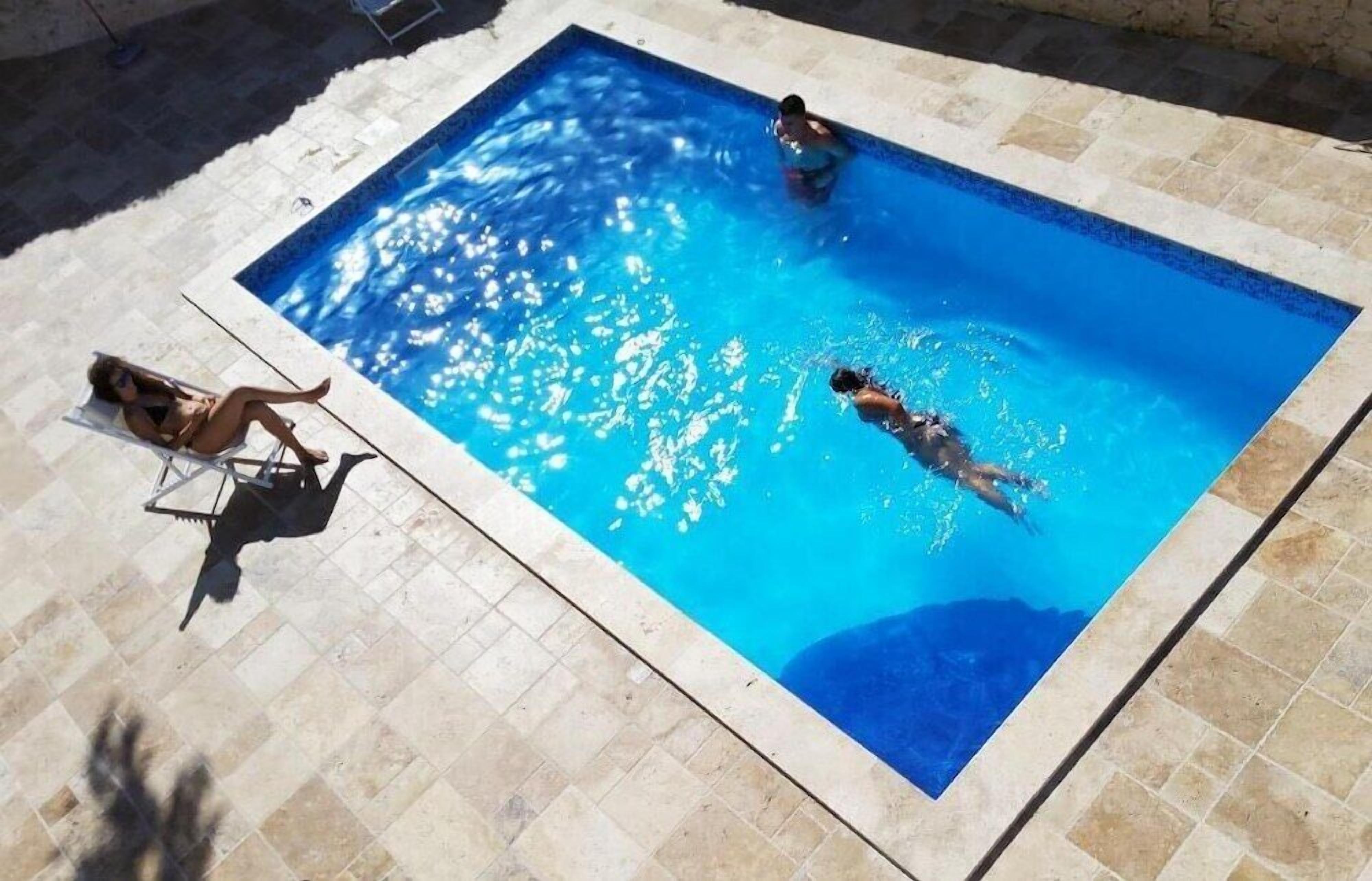 Une piscine rectangulaire dans laquelle nagent deux personnes.
