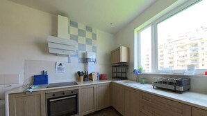 A modern kitchen with a built-in oven, a window with a view of buildings, and a checkered backsplash. - Inhawi Hostel (St. Julian's)