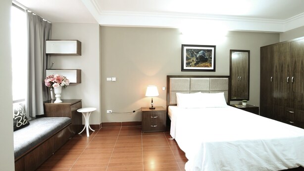 A hotel room with a bed, bedside table, lamp, and a large wardrobe. - Istay Hotel Apartment 1 (Hanoi)