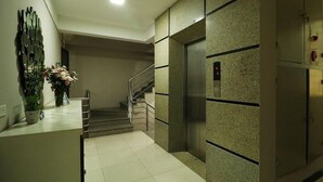 A modern elevator with a digital display, a staircase with metal railings, and a wall-mounted decorative mirror. - Istay Hotel Apartment 1 (Hanoi)